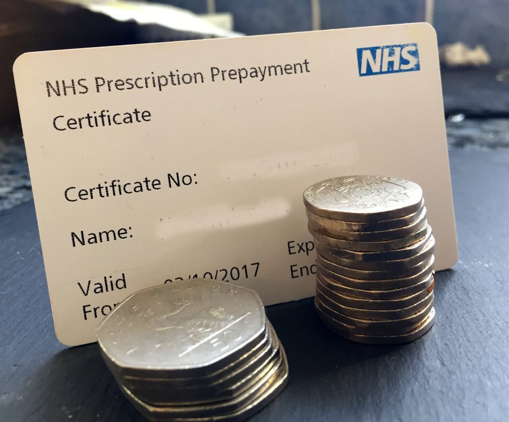 Close-up of a prescription prepayment certificate with cash beside it, illustrating cost savings