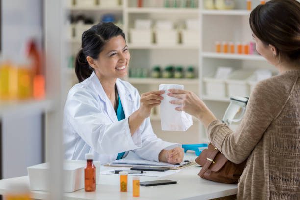Pharmacist handing prescribed medication to a customer at a pharmacy counter using a Prescription Prepayment Certificate