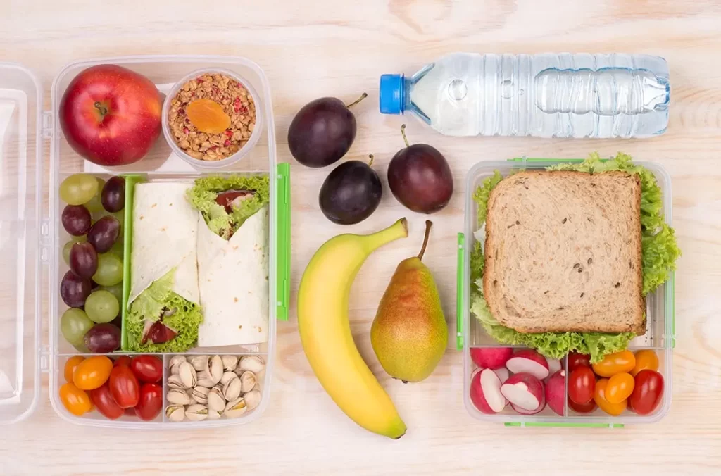 Healthy packed school lunch with fruit, sandwiches, and reusable containers