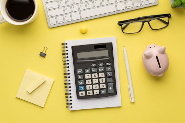 Simple budgeting setup showing calculator and notebook used to organise money with the 50/20 rule